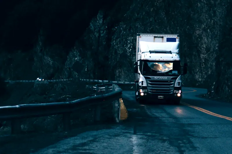 Caminhão com os faróis acesos numa estrada de serra ao anoitecer (foto ilustrativa)
